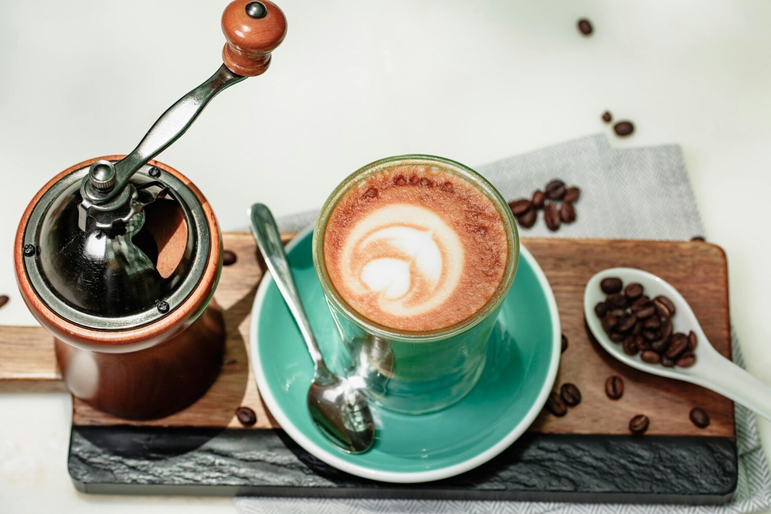 A stylish coffee setup with a latte art cup, grinder, and coffee beans on a tray, perfect for coffee lovers.